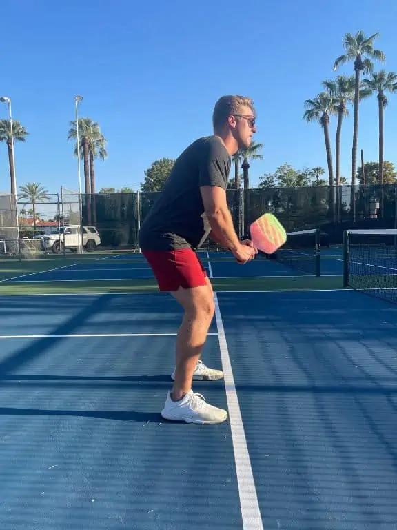 pickleball player standing in a ready position for a dink at the kitchen line. 